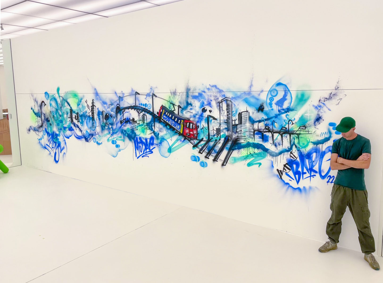 Fresque street art de Philippe Baro : train, ponts et skyline en bleus et turquoise